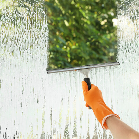 Woodlands Window Cleaning & Pressure Washing Service, LLC. | Window Cleaning Male janitor cleaning window with squeegee, closeup